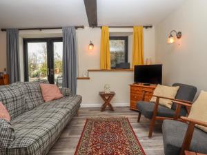 un salon avec un canapé et une télévision dans l'établissement Warren Cottage, à Sidmouth