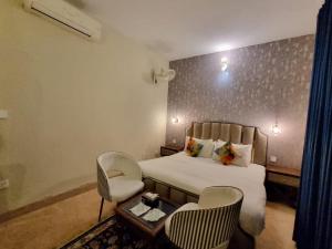 a bedroom with a bed and two chairs and a table at The Life Style Lodges opp Centaurus Mall in Islamabad