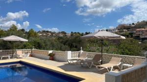 een zwembad met stoelen en parasols op een patio bij Casa Biamar in Calpe