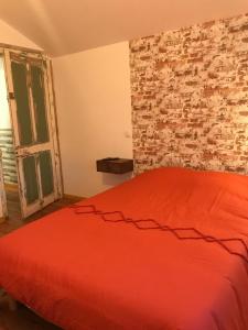 1 dormitorio con cama roja y pared de ladrillo en La chambre aux briques oranges, en Saint-Dizier