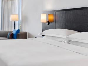 uma cama com lençóis brancos e almofadas num quarto em Hilton Rose Hall Resort & Spa em Montego Bay