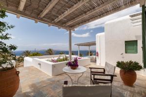 a patio with a bathtub and chairs and a table at Fos Apartments Mykonos in Agios Ioannis Mykonos