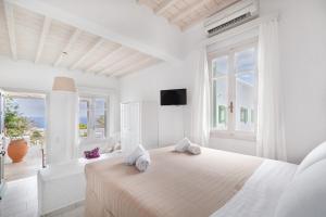 a white bedroom with a large bed and a balcony at Fos Apartments Mykonos in Agios Ioannis Mykonos