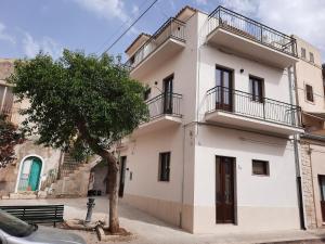 a white building with a tree in front of it at Family Rooms Scicli Centro in Scicli