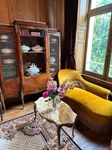 ein Wohnzimmer mit einem gelben Sofa und einem Tisch in der Unterkunft Chambre de Princesse avec Grande Salle de Bain in Blet