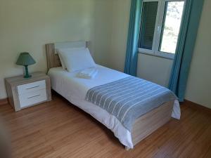ein Schlafzimmer mit einem Bett, einem Nachttisch und einem Fenster in der Unterkunft Residência do Saramago in São Vicente