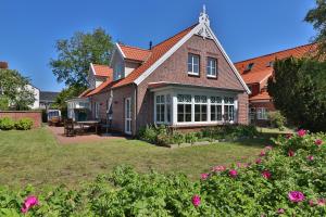 une grande maison en briques avec une cour fleurie dans l'établissement Bi'n Eekboom, à Langeoog