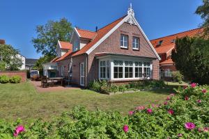a large brick house with a yard with flowers at Bi'n Eekboom in Langeoog