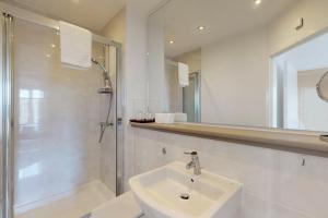 a white bathroom with a sink and a shower at Lovely Apartment with Balcony - 3 min to Station in London