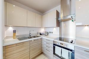 a kitchen with white cabinets and a sink at Lovely Apartment with Balcony - 3 min to Station in London