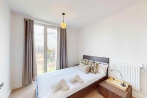 a bedroom with a bed with a large window at Lovely Apartment with Balcony - 3 min to Station in London