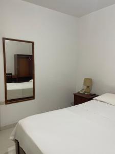 um quarto com uma cama branca e um espelho em Hotel Country Boutique em Piura