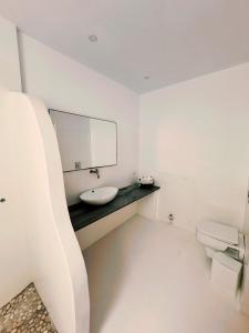 a white bathroom with a sink and a mirror at Sofia's Bungalows Mykonos in Mikonos