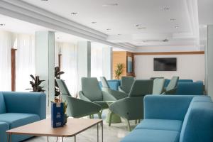 a waiting room with blue chairs and a tv at Hotel Vista Park in Can Picafort