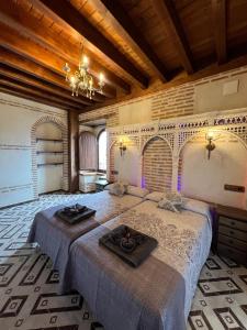 a bedroom with two beds and a chandelier at Casa Rural EL TORREÓN in Fontiveros +16 photos