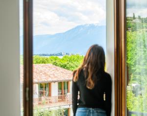Eine Frau, die aus dem Fenster auf einen Berg schaut. in der Unterkunft Residence Molino - Holiday Apartments in Manerba del Garda