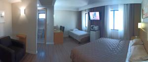 a bedroom with a bed and a couch and a desk at Hotel Flat Guarulhos Apto1808 in Guarulhos +19 photos