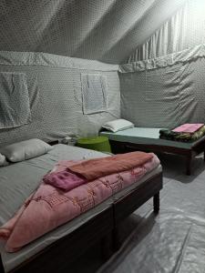 Zimmer mit 2 Betten und einem Tisch in einem Zelt in der Unterkunft Hill dew homestay in Uttarkāshi