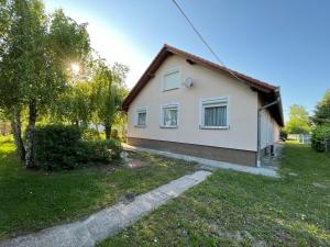 a small white house in a yard with trees at R-Home Apartman in Zamárdi