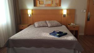 a bedroom with a bed with two night stands and two tables at Hotel Flat Guarulhos Apto1808 in Guarulhos