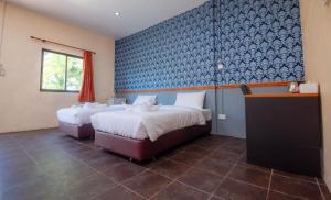 1 dormitorio con 2 camas y pared azul en NaLinNaa Resort Buriram ณลิ์ณน่า รีสอร์ท บุรีรัมย์, en Buriram