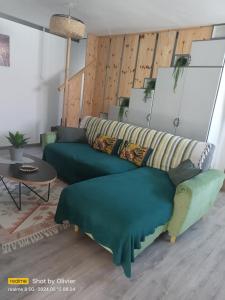 uma sala de estar com um sofá verde e uma mesa em kaz'manou em Saint-Benoît
