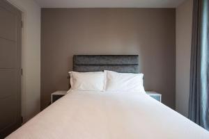 a bed with white sheets and pillows in a bedroom at Stunning 2BR next to the City Airport BHD - Free Parking in Belfast
