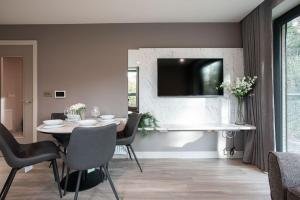 a dining room with a table and a television on a wall at Stunning 2BR next to the City Airport BHD - Free Parking in Belfast