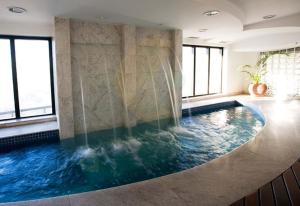 a large swimming pool in a room with windows at Hotel Guarulhos Slaviero Apto1808 in Guarulhos