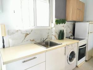 - une cuisine blanche avec un évier et un lave-vaisselle dans l'établissement Vasiliki Holidays Private Apartment Chalkidiki, à Flogita