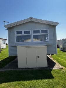 a garage with two white doors in a yard at MOONSTONE Lymington in Leysdown-on-Sea