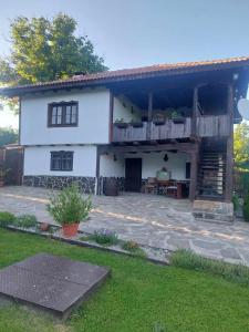 uma casa branca com um deque e um pátio em Митровата къща em Raynovtsi