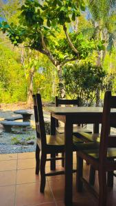 drewniany stół i krzesła ze stołem i drzewami w obiekcie Mal Pais Surf Camp w mieście Playa Santa Teresa