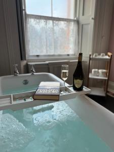 a bath tub with a bottle of wine and a glass at Clone Country House in Aughrim