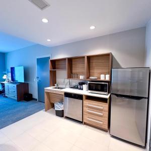 a kitchen with wooden cabinets and a stainless steel refrigerator at Home2 Suites By Hilton Fort Walton Beach in Fort Walton Beach
