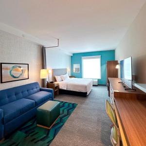Home2 Suites By Hilton Fort Walton Beach في شاطئ فورت والتون: غرفة في الفندق مع أريكة زرقاء وسرير