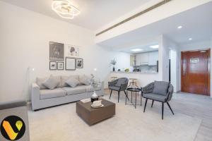 sala de estar con sofá, sillas y mesa en Vogue - The Greens and Views, en Dubái