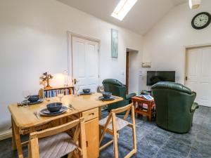 a living room with a wooden table and green chairs at Yr Hen Ysgubor in Carmarthen
