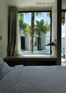 a bedroom with a bed and a window with palm trees at KAYA Uluwatu in Uluwatu