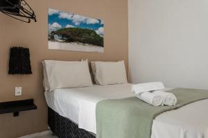 um quarto com uma cama com lençóis brancos e toalhas em Pousada Principal em Jericoacoara