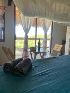 ein Bett mit Handtüchern, einem Tisch und einem Fenster in der Unterkunft La Aldea Zipolite in Zipolite