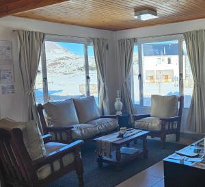 a living room with a couch and chairs and windows at Nothofagus in Caviahue