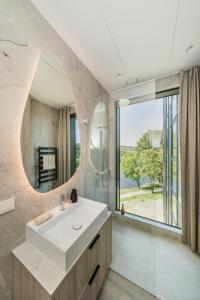 a bathroom with a white sink and a large window at Kaunorama Riverside Suite in Kaunas