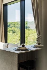 two wine glasses sitting on a table with a window at Kaunorama Riverside Suite in Kaunas