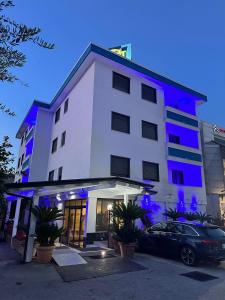 a white building with a car parked in front of it at Hotel Clinton in Casoria