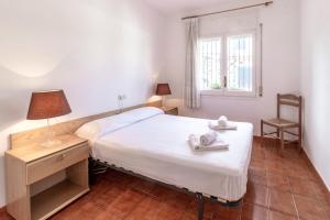 um quarto com uma cama branca e uma janela em Carboneras 54 Apartamento acogedor cerca del mar em Girona