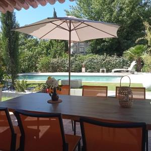 einen Tisch mit einem Sonnenschirm vor einem Pool in der Unterkunft Villa La Croisette in Sainte-Maxime