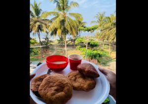 a plate of food with cookies and a view of the ocean at Nenapu Beachfront Mangalore in Mangalore