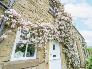 a house with pink flowers climbing up the side of it at Wayside Cottage in Consett