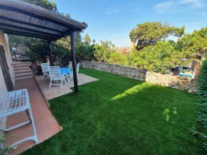 un jardín con mesa, sillas y pared de piedra en BellaVista Monolocale, en Cala Bitta